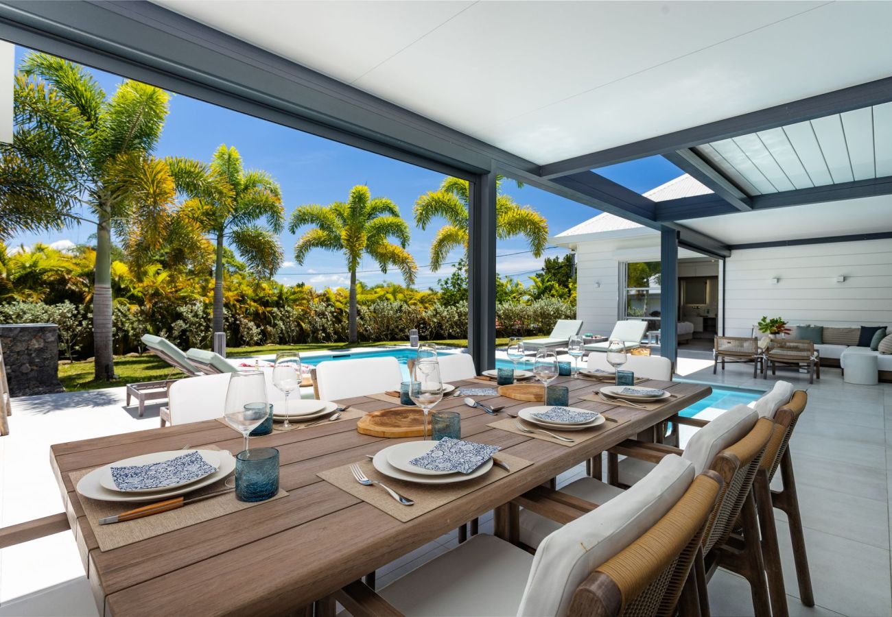 Dining table on the shaded terrace overlooking the pool at Villa Koulirou Émeraude