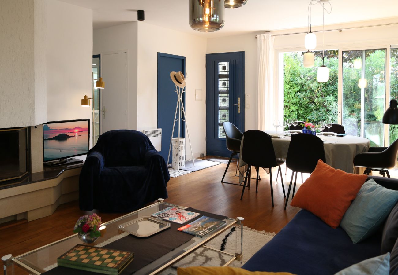 Living room and dining room in a rental in Saint-Malo with large windows opening onto the garden