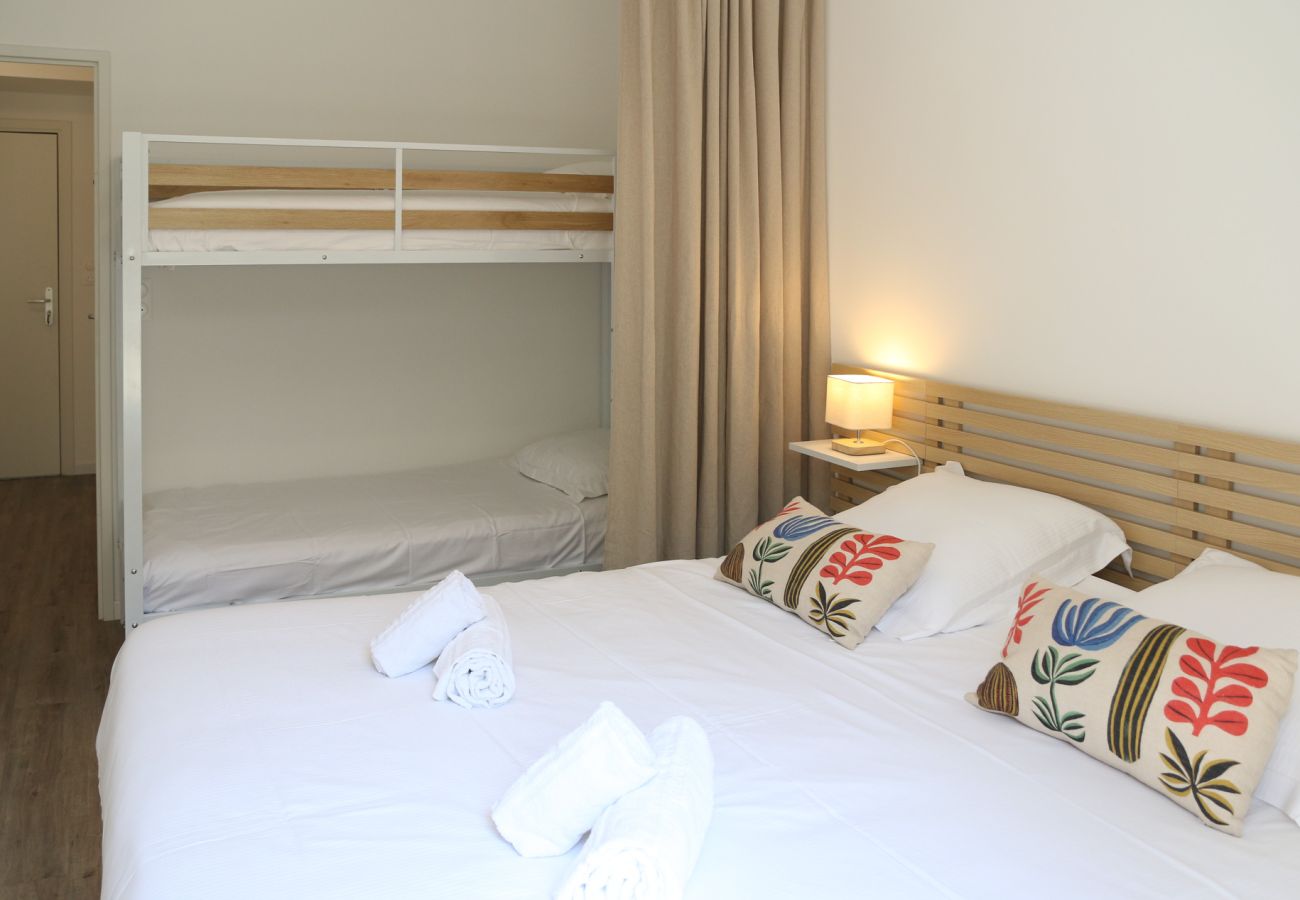 A spacious bedroom with a double bed and bunk beds in a holiday flat in Cancale