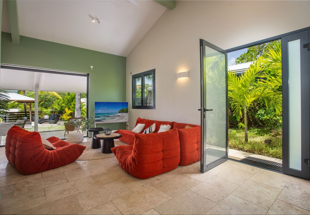 Bright living room opening onto the terrace, pool, and tropical garden at Villa Bohème, Le François, Martinique.
