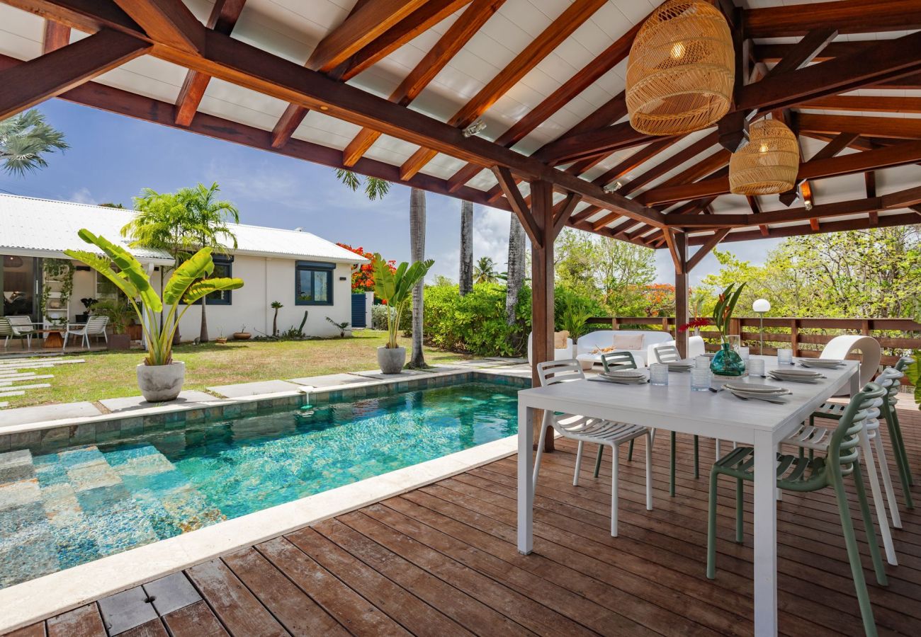 Outdoor dining area under a traditional carbet beside the pool at Villa Bohème, Le François, Martinique.
