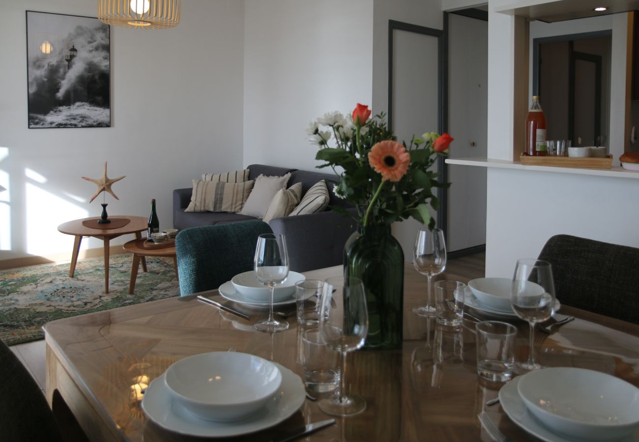 Living room with a set dining table, a cosy lounge and nautical décor in Cancale