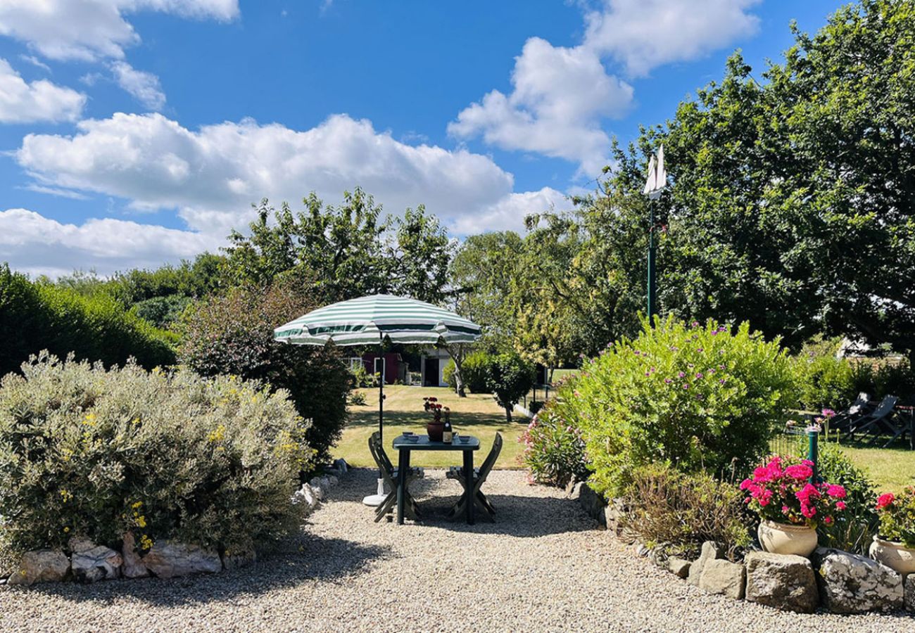 Jardin arboré et fleuri avec table extérieure sous parasol aux Phares du Haut Bout à Cancale