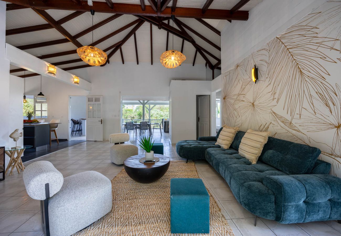 Salon moderne redécoré avec charpente apparente, ouvert sur une terrasse avec vue jardin et piscine en Martinique.