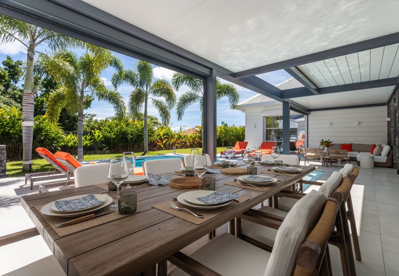 Table de repas sur la terrasse ombragée avec vue sur la piscine de la Villa Koulirou Corail