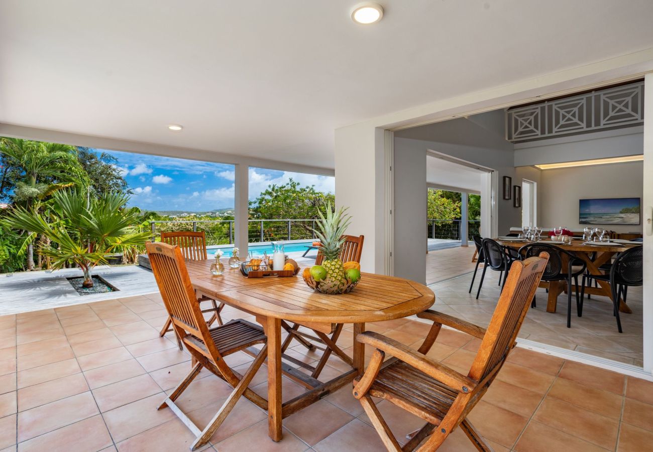 Salle à manger extérieure sur terrasse couverte avec vue sur la mer, la piscine de la villa Garden Bay en Martinique.