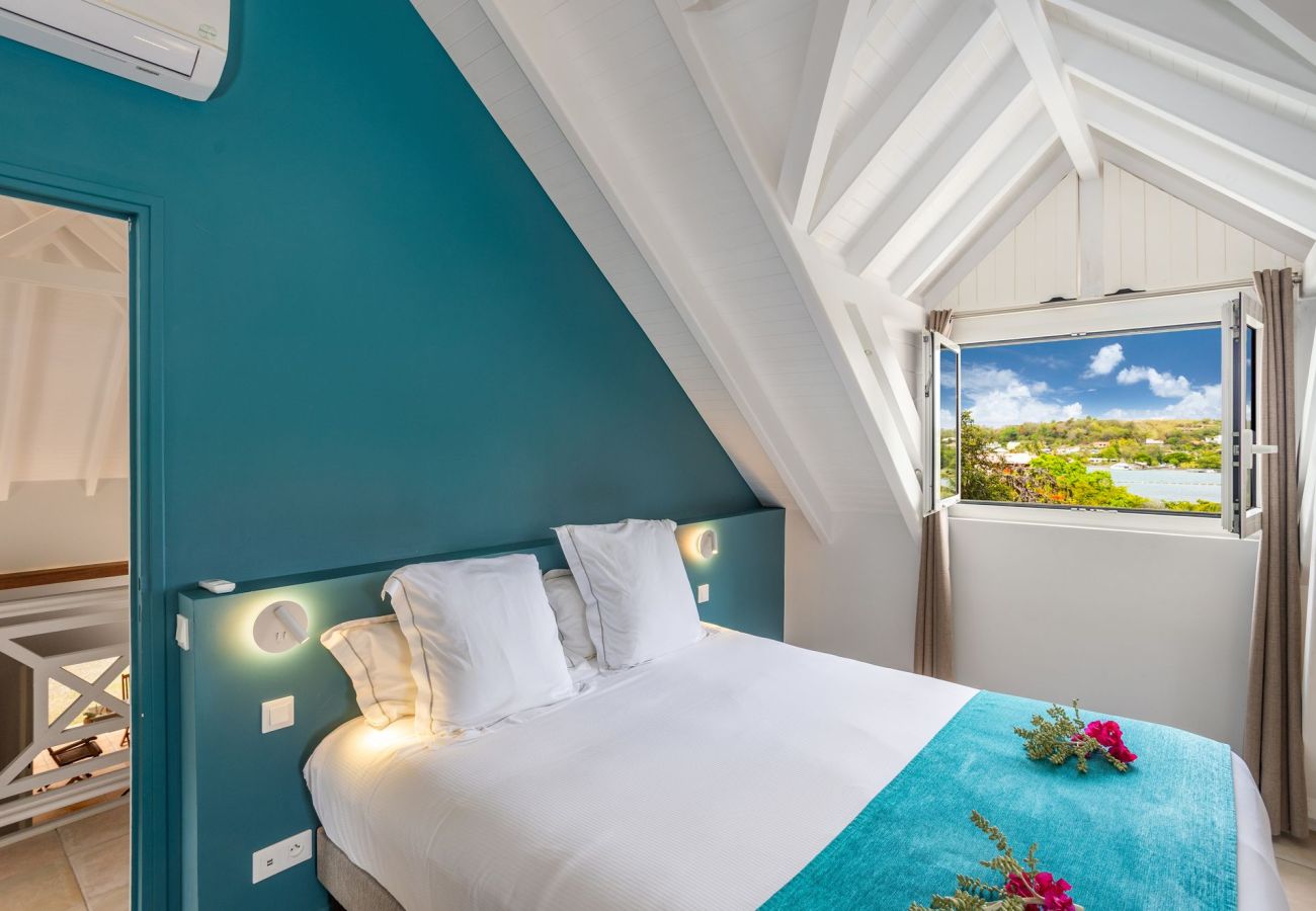 Chambre climatisée avec vue mer, espace détente et salle de douche privative à la villa Garden Bay.
