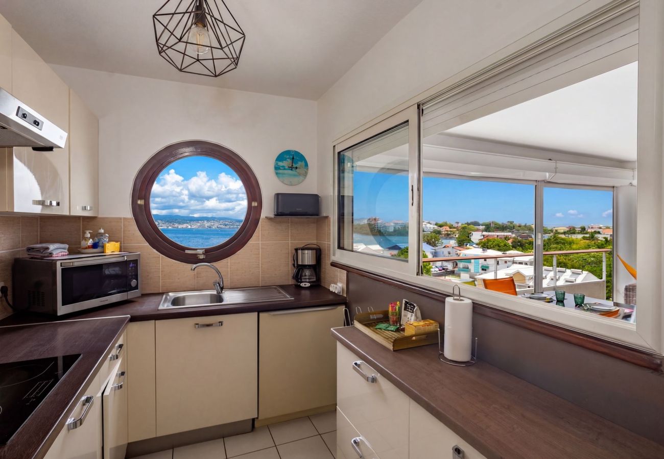 Cuisine équipée avec vue panoramique sur la baie de Fort-de-France à l'appartement Ti'Bato aux Trois-Îlets.